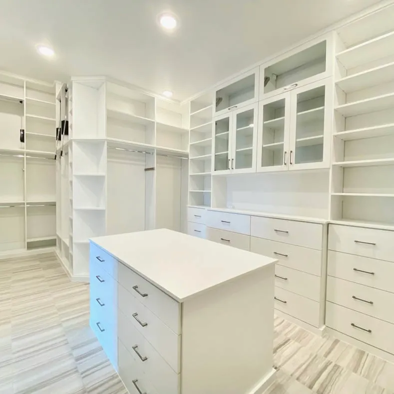 Custom white walk-in closet with a center island, glass-front cabinets and open shelving