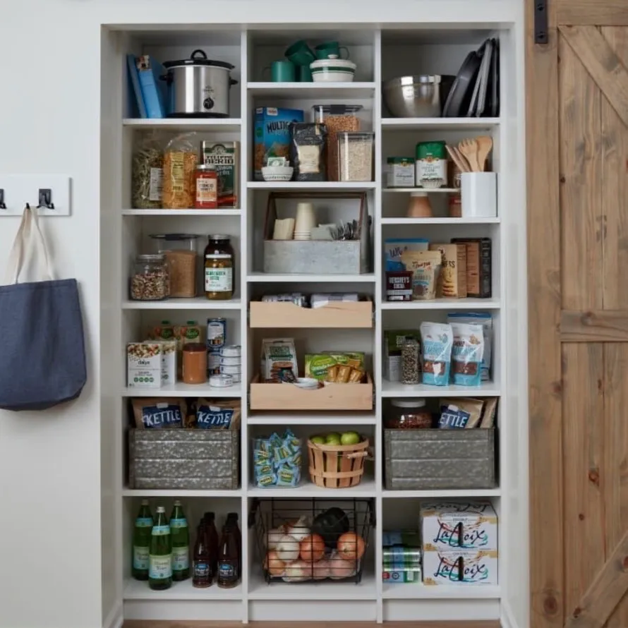 Organized pantry closet with labeled bins, baskets and jars on open wood shelving